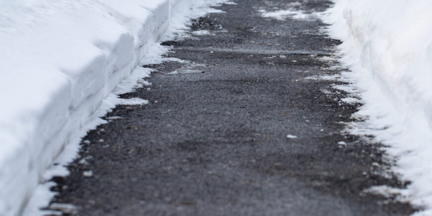 Winter road with salt for melting snow Winter sidewalk cleared of with snow.