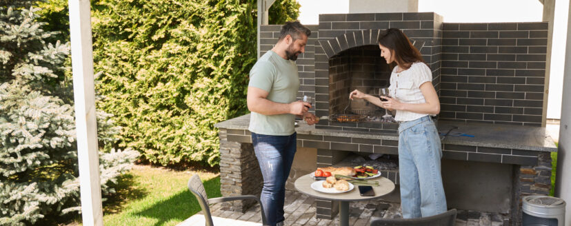 Spouses cook food together in the backyard, people in comfortable casual clothes