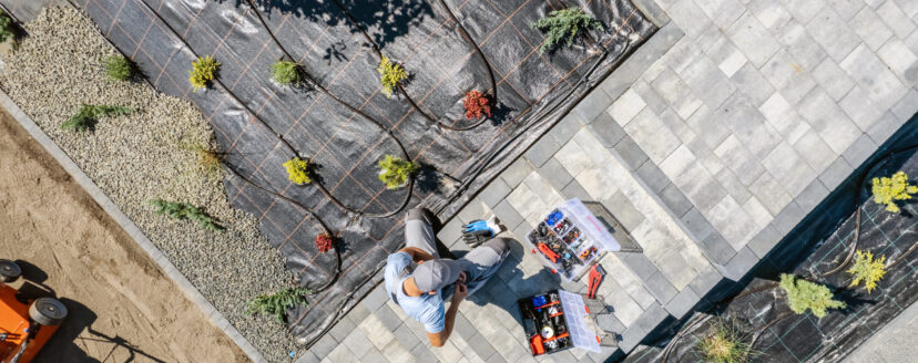 Caucasian Professional Garden Systems Technician Installing Drip Irrigation in Newly Developed Residential Backyard Garden. Landscaper Job.